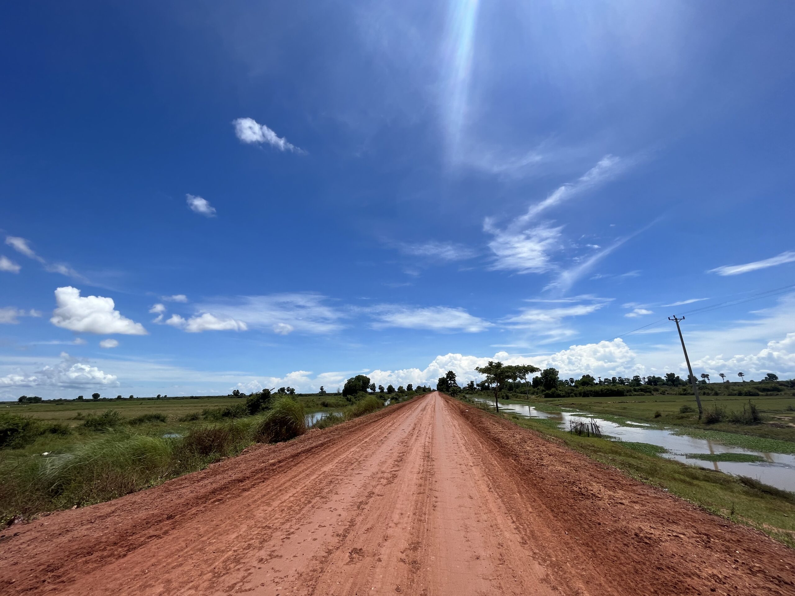 草地の間をまっすぐに延びる赤土の道